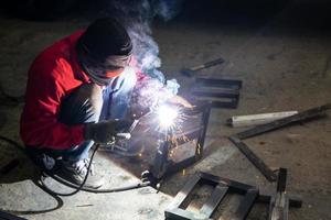 Welder used grinding stone on steel in factory with sparks, Welding process at the industrial workshop, hands with instrument in frame. photo