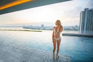 Young woman enjoying and relaxing at poolside. Slim young girl model in white bikini  by the pool. photo