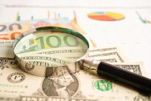 Magnifying glass on US dollar and EURO banknotes and graph, finance business trade concept. photo