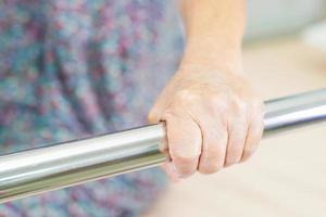 Asian elder senior woman patient holding bed rail while lie down with hope waiting her family in hospital. photo