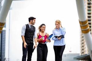 young business people discussing while walking on sidewalk at outside. photo
