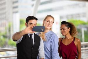 young business people take photo by mobile phone while walking on sidewalk at outside.