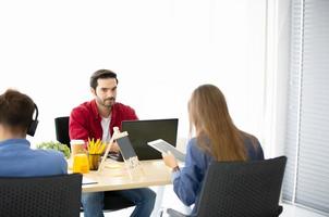Diverse group of young business people discussing a work project while sitting together at a table in a modern office. coworking concept photo