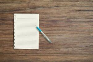 Blank white notebook pad on wood desk background with copy space. Top down photo