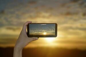 mano turística tomando una foto del maravilloso fondo de la puesta de sol.