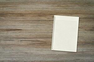 Blank white notebook pad on wood desk background with copy space. Top down photo