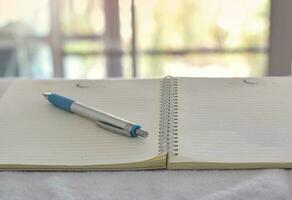 Close up of pen in notebook on office desk with blurry background. photo