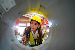 la capataz de la trabajadora o el trabajo del trabajador en el sitio de la fábrica revisan la máquina o los productos en el sitio. ingeniero o técnico revisando material o máquina en planta. industrial y fábrica. foto