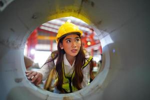 la capataz de la trabajadora o el trabajo del trabajador en el sitio de la fábrica revisan la máquina o los productos en el sitio. ingeniero o técnico revisando material o máquina en planta. industrial y fábrica. foto