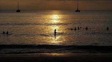 schöner sonnenuntergang mit silhouetten von menschen genießen sie den ozean. video