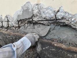 The damaged wall is visible to the internal steel bar. The plaster should be repaired to make it work. photo