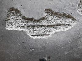 The damaged wall is visible to the internal steel bar.  The plaster should be  repaired With mortar to make it work. photo