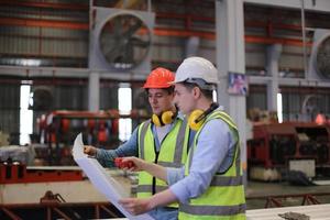 el capataz de los trabajadores de la industria o el trabajo de los trabajadores en el sitio de la fábrica revisan la máquina o los productos en el sitio. ingeniero o técnico revisando material o máquina en planta. industrial y fábrica. foto