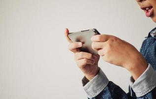 niño jugando juegos en teléfonos inteligentes, niño mano sosteniendo un teléfono inteligente foto