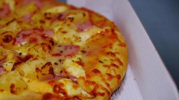 Pizza de chorizo y jamón con queso. la pizza en la caja de entrega diaria fue entregada sobre la mesa de mármol. video