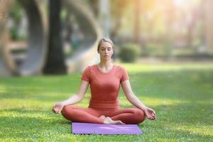 longitud completa de mujer ejerciendo yoga en la alfombra en el parque foto