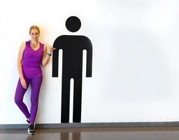retrato de mujeres con ropa deportiva de pie junto a un personaje gráfico masculino contra una pared blanca foto
