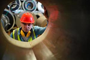 el capataz de los trabajadores de la industria o el trabajo de los trabajadores en el sitio de la fábrica revisan la máquina o los productos en el sitio. ingeniero o técnico revisando material o máquina en planta. industrial y fábrica. foto