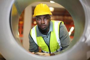 ingeniero industrial masculino con casco de seguridad mientras está de pie en una fábrica industrial pesada. el mantenimiento que busca trabajar en maquinaria industrial y verificar la configuración del sistema de seguridad en fábrica. foto