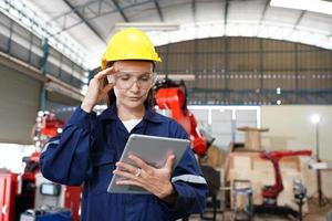 Professional young industrial factory woman employee working with machine part, checking and testing industrial equipment and robot arms in large Electric electronics wire and manufacturing plant photo