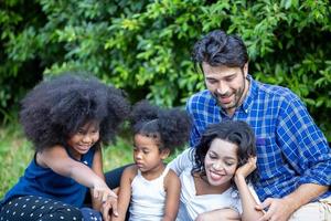 Portrait of happy young african American family with little kids sit relax on couch cuddling, smiling black parents rest on sofa hug preschooler children posing for picture at home together photo