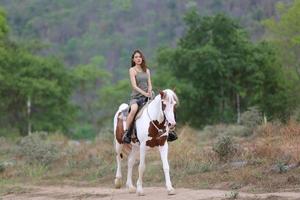 mujer joven con su caballo en la luz del atardecer. fotografía al aire libre con una modelo de moda. estado de ánimo de estilo de vida foto