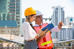 The engineer and business woman checking on clipboard at construction site building. The concept of engineering, construction, city life and future. photo