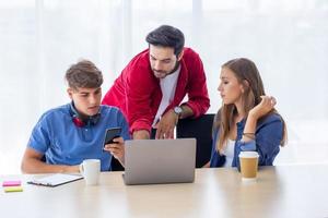 Diverse group of young business people discussing a work project while sitting together at a table in a modern office. coworking concept photo