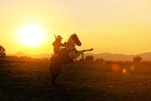 vaquero a caballo contra una hermosa puesta de sol, vaquero y caballo a primera luz, montaña, río y estilo de vida con fondo de luz natural foto