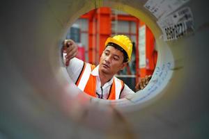 el capataz de los trabajadores de la industria o el trabajo de los trabajadores en el sitio de la fábrica revisan la máquina o los productos en el sitio. ingeniero o técnico revisando material o máquina en planta. industrial y fábrica. foto