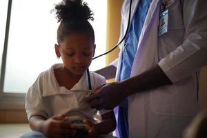 Black skin doctor checking up kid body in clinic. photo
