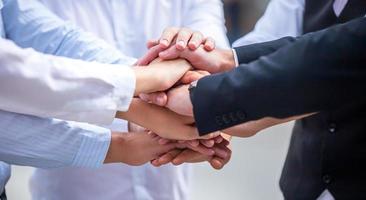 Stack of hands. Unity and teamwork concept. Close up top view of young business people putting their hands together photo