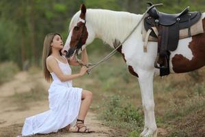 mujer joven con su caballo en la luz del atardecer. fotografía al aire libre con una modelo de moda. estado de ánimo de estilo de vida foto