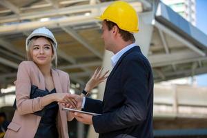 The engineer and business woman checking on clipboard at construction site building. The concept of engineering, construction, city life and future. photo