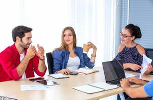 grupo diverso de jóvenes empresarios discutiendo un proyecto de trabajo mientras se sientan juntos en una mesa en una oficina moderna. concepto de coworking foto