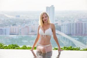Young woman enjoying and relaxing at poolside. Slim young girl model in white bikini  by the pool. photo