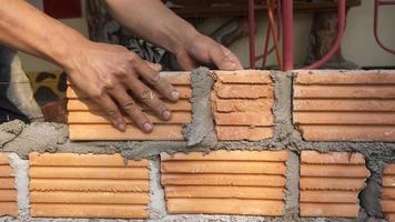Bricklayer worker installing brick masonry on exterior wall photo