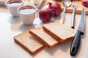 preparar pan con taza de té y utensilios de cocina, egetable y carne en la mesa foto