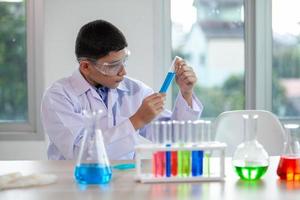 Little boy mixes chemicals in beakers. kids with test tube making experiment at school laboratory. photo