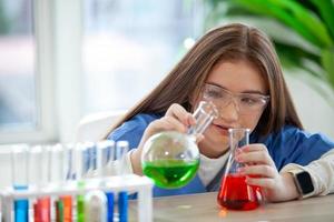 Students mixes chemicals in beakers. Chemistry student mixes chemicals in science class photo