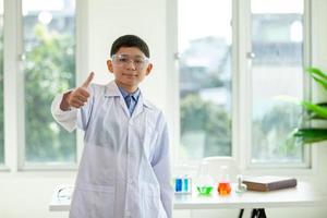 niño pequeño mezcla productos químicos en vasos de precipitados. niños de pie con tubo de ensayo en el laboratorio de la escuela.