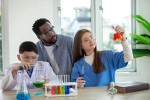 Students mixes chemicals in beakers. enthusiastic teacher explains chemistry to children, chemistry student showing new experiment to teacher science class photo