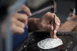 Silversmith using hammers and steel engraved  pattern on silver plate for accessory handmade