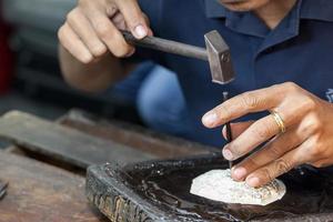 orfebre usando martillos y patrón grabado de acero en placa de plata para accesorios hechos a mano foto