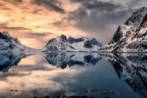 Snow mountain reflection on arctic seashore at sunset
