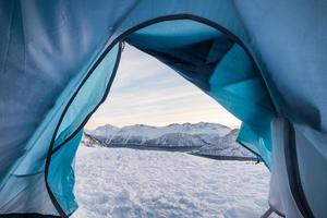 Relaxing inside tent camping opening with snowy mountain photo