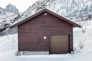 almacén marrón de madera con puerta enrollable en la nieve foto