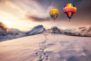 Hot air balloons flying on snowy mountain with footprint on peak photo