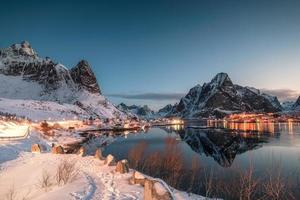 Fishing village illuminated in mountain valley reflection on winter at dawn photo