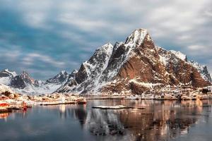 montaña nevada con pueblo escandinavo en el océano ártico en invierno foto
